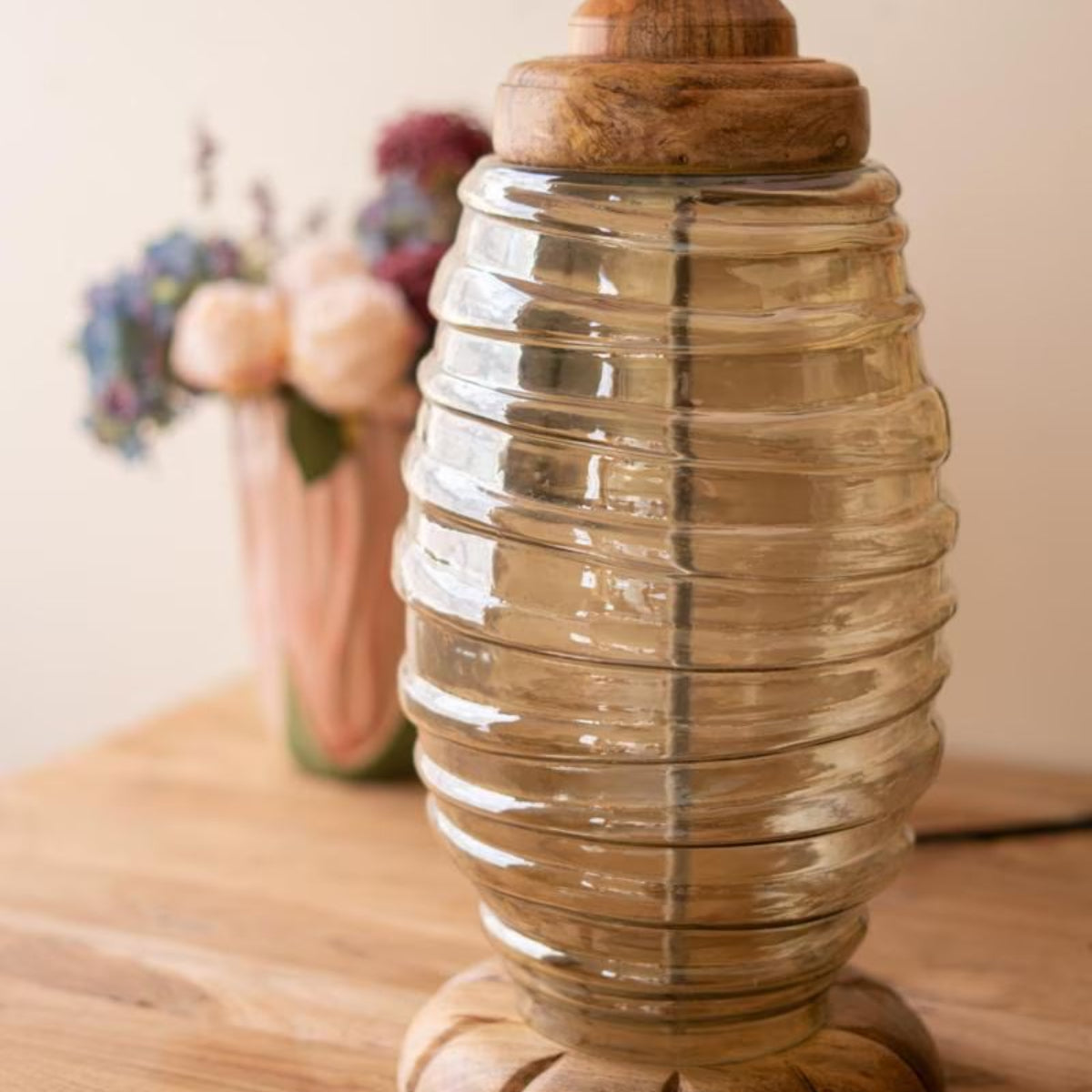 Detail of glass lamp base and wood foot with flowers