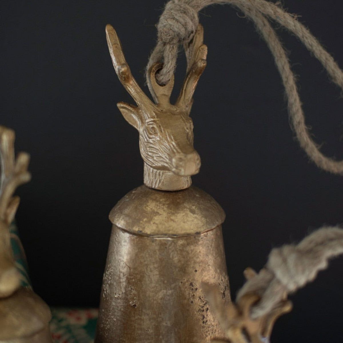 Three distressed gold metal bells with stag finials
