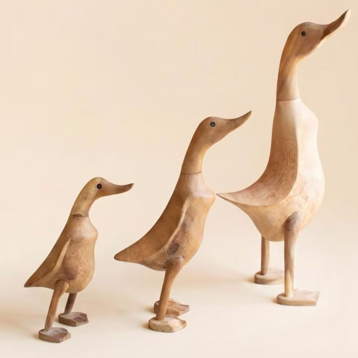 Set of 3 natural wood duck figures on a white background