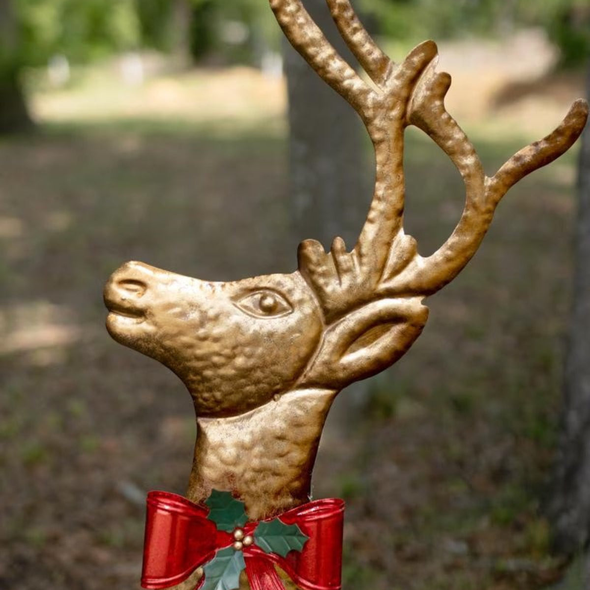Leaping Gold Reindeer Yard Stake, antique gold metal reindeer with red bow in a garden