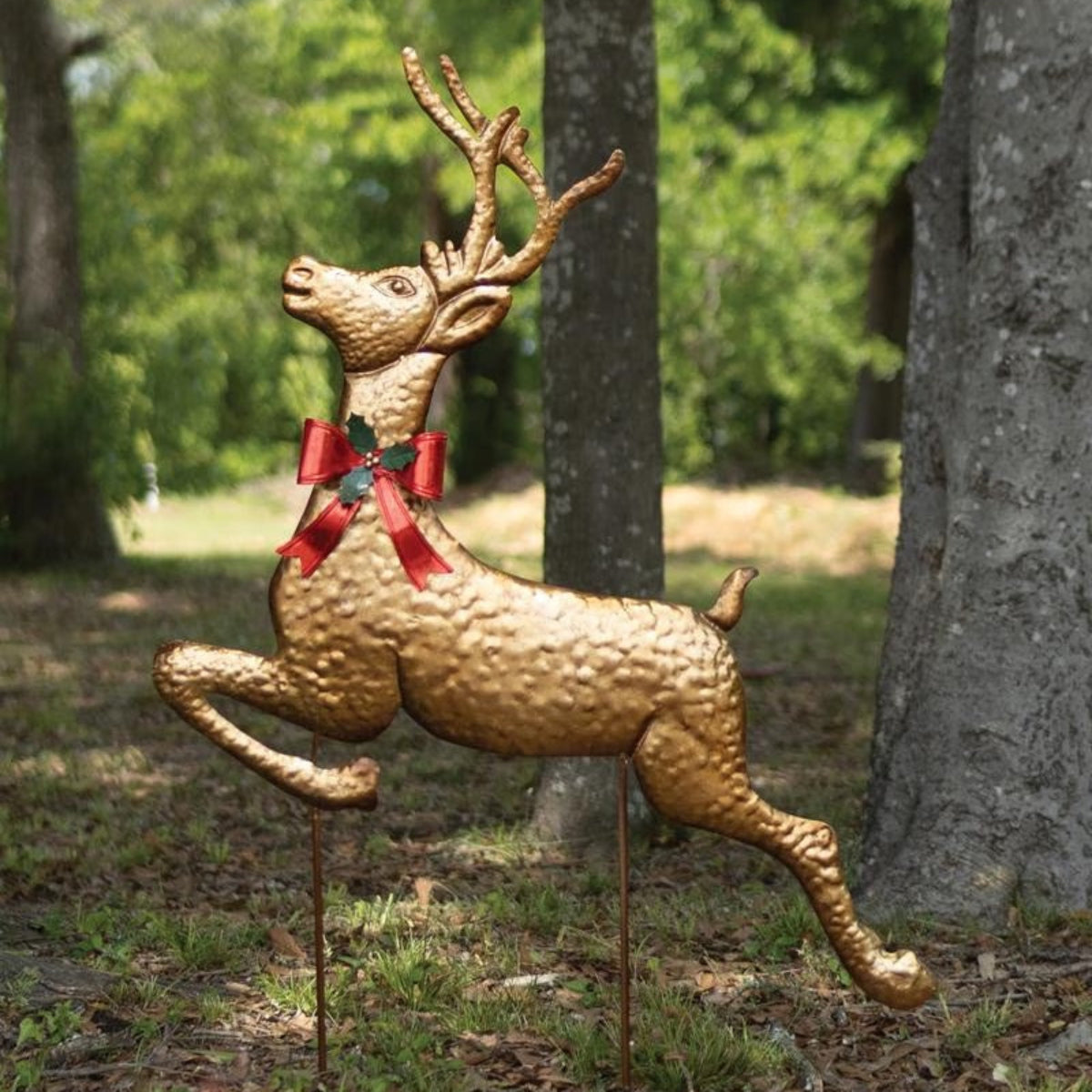 Leaping Gold Reindeer Yard Stake, antique gold metal reindeer with red bow in a garden