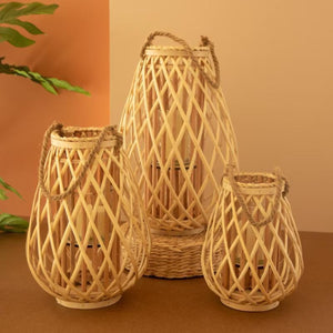 Set of 3 natural willow lanterns with glass inserts on a wood surface