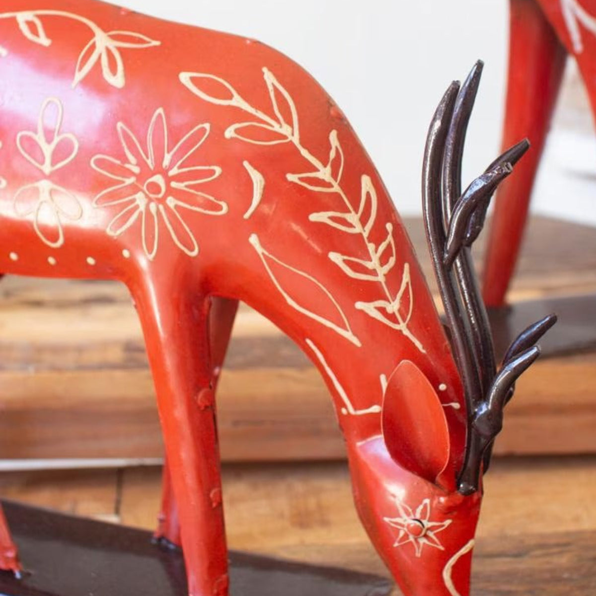 Grazing red folk reindeer with head down and dark antlers