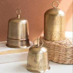 Three antique brass bells displayed on a tabletop