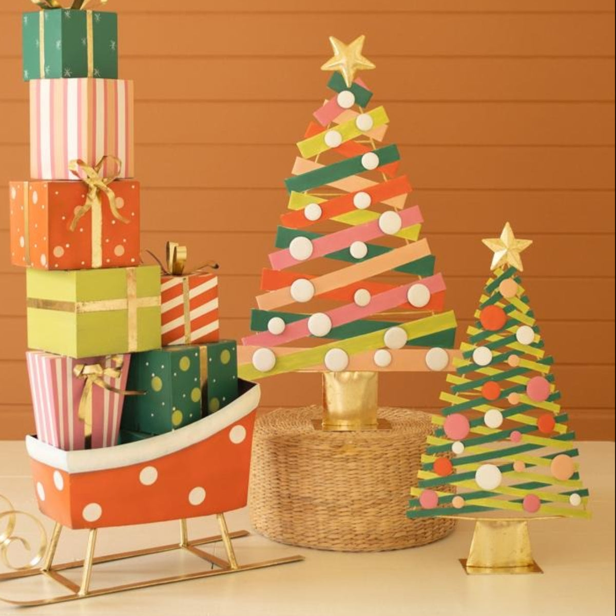 Striped metal Christmas trees styled with a red sleigh and wrapped gifts