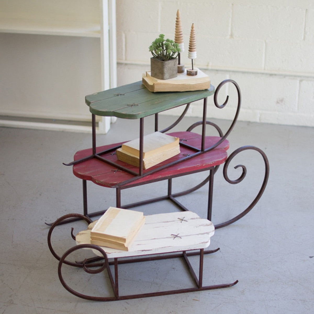 Three distressed painted wood sleighs on metal runners