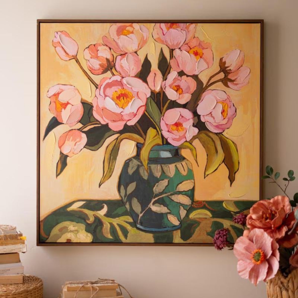 Framed pink peonies in a vase painting hung above a table with baskets