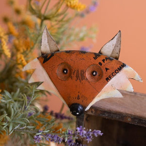 Close-up of distressed metal fox head with flowers