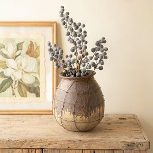 Rustic ceramic vessel with wire detail holding dried stems