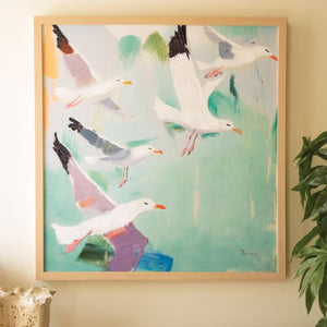 Seaside Gulls in Flight Canvas Art, framed coastal painting hung above a console