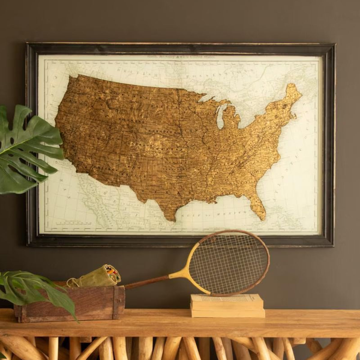 Vintage gold United States map framed art above a rustic console on a dark wall