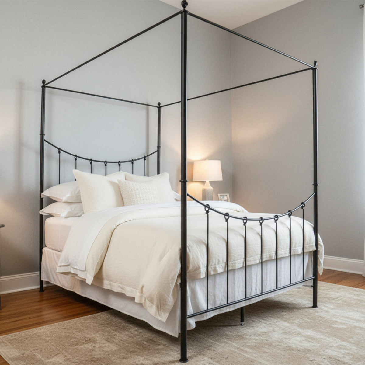 A canopy bed with a metal frame, featuring a headboard and footboard, in a room with a wooden floor and a textured wall.
