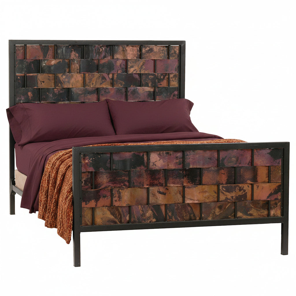 A full view of a double-sized iron bed with a copperweave design, featuring a headboard and footboard with hand-applied copper panels, in a room setting with bedding.