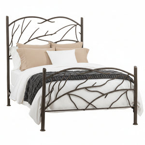 A wrought iron bed frame with a design that resembles windblown tree limbs, with a beige bedsheet on it.
