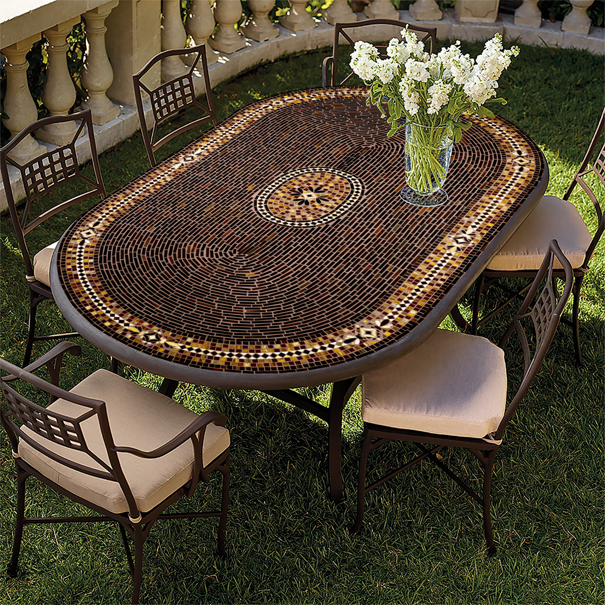 An oval bistro table with a mosaic top featuring a geometric pattern, set on a grassy outdoor area with several chairs around it.