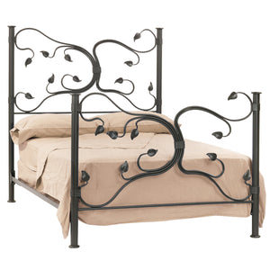 A full-sized Willowmere Vine Iron Bed with a beige bedsheet, featuring hand-forged iron with leaf-like patterns.