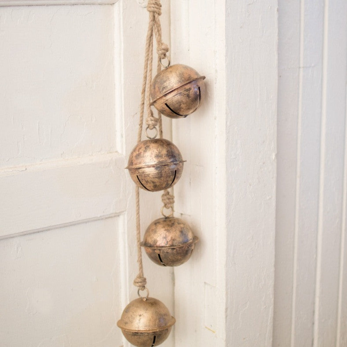 Aged metal hanging bells in distressed gold on a jute rope
