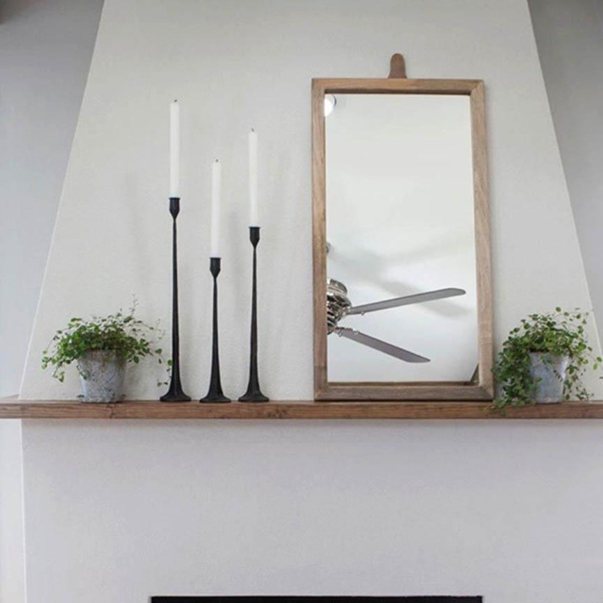 Cast iron taper candlesticks on a wood shelf with a mirror