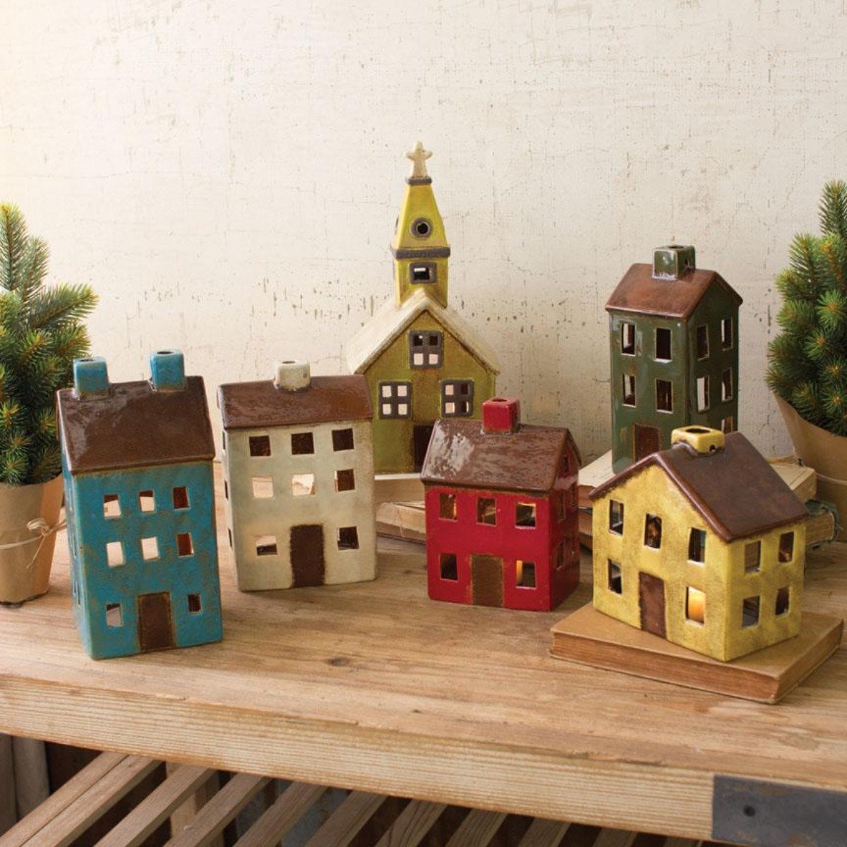 Colorful ceramic Christmas village church and houses on a wood shelf