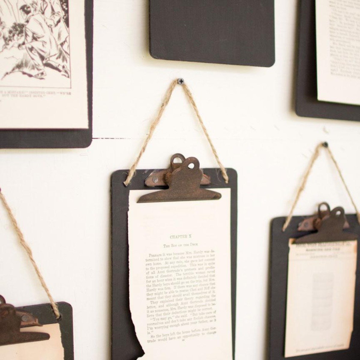 Black clipboard photo holders with jute hangers displaying photos on a wall
